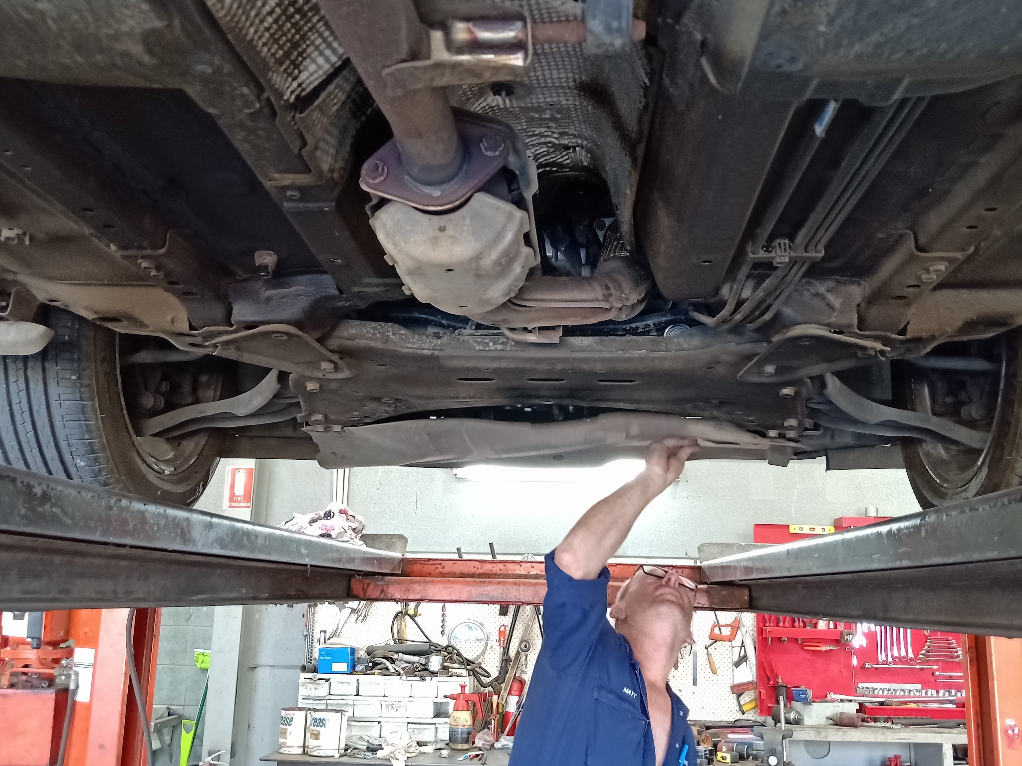 A mechanic working underneath a car on the hoist inside the Matson Motors workshop